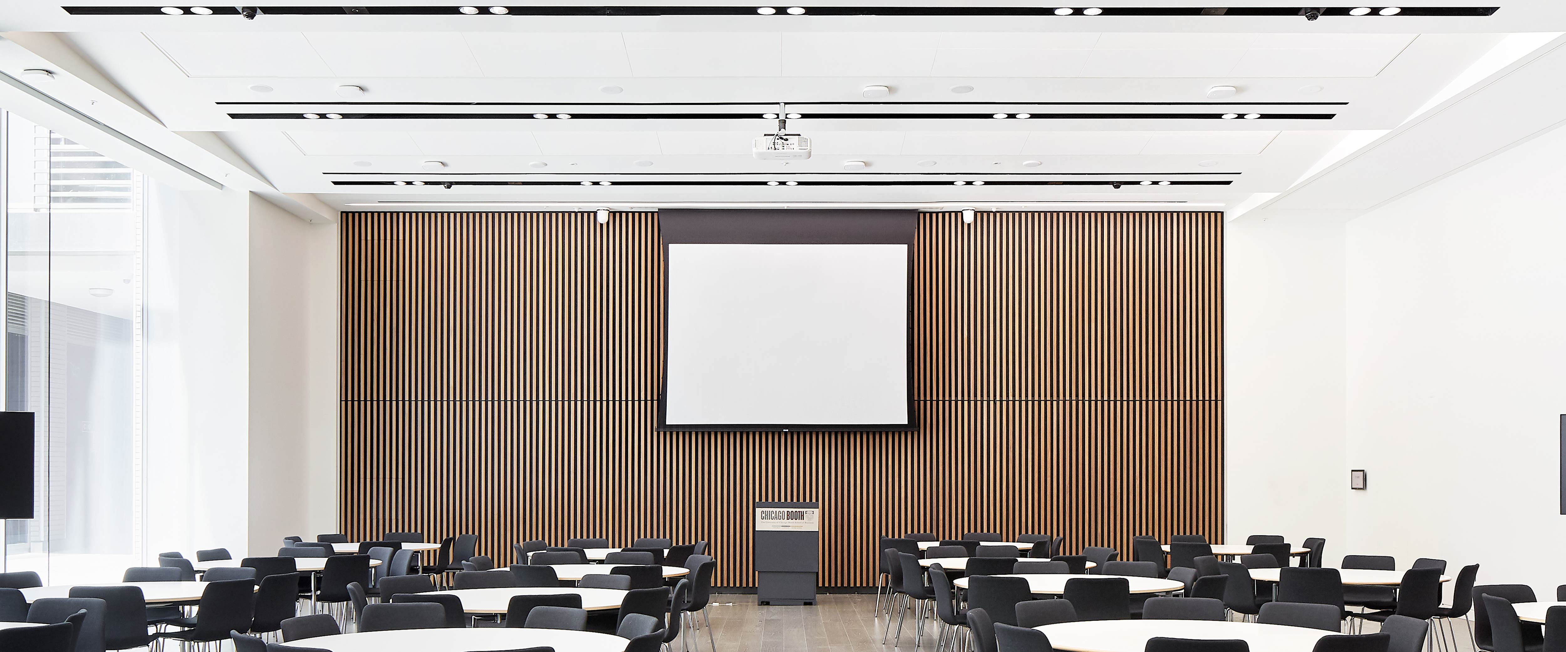 Large conference hall with a projector, projector screen, and podium at centre